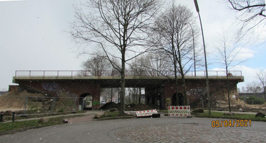 Die Wilhelmsburger Reichsstraße rechts und links der Brücke ist schon abgerissen. Die rote Klinkerbrücke mit den beiden halbrunden Durchgängen für Fußgänger steht hinter ein paar Bäumen am Ende des Wendehammers der Rothenhäuser Straße.