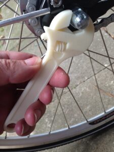 Eine Hand zieht mit einem Schraubenschlüssel eine Schraube an einem Fahrrad fest