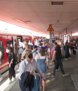 Viele Menschen laufen über den Bahnsteig von einem Zug zum andern.