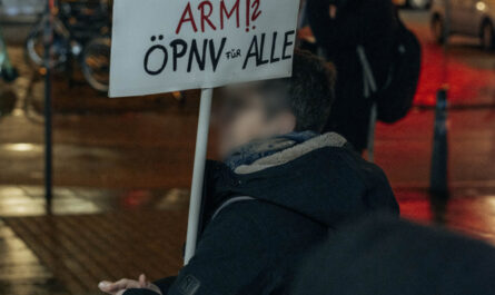 Eine Person hät ein Schild in der Hand auf dem steht: Kriminell oder nur arm? ÖPNV für Alle.