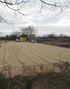 Die Baustelle der neuen Schule, eine große planierte Sandfläche