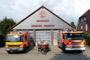 Das Gerätehaus der Feuerwehr in Kirchdorf mit den großen Garagentoren. Davor stehen zwei Löschfahrzeuge und ein Feuerwehrboot.