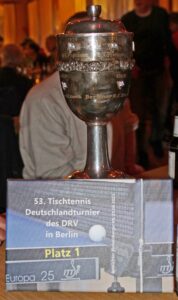 Ein Pokal auf einem Tisch. Davor eine Textkarte: 33. Tischtennis Deutschlandtournier des DRV in Berlin Platz 1.