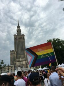 Demonstrationszug vor dem Kulturpalast in Warschau mit Regenbogen-Fahne.