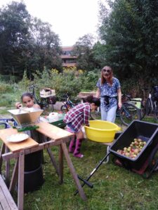 2 Kinder und eine Erwachsene waschen und pressen Äpfel in einem Garten