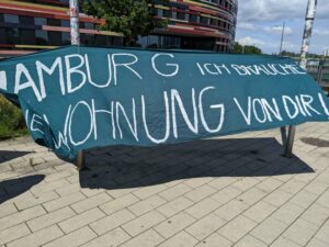 Ein großes. blaues Transpararent hängt vor der Behörde für Stadtentwicklung und Wohnen. Darauf steht "Hamburg, ich brauche eine Wohnung von Dir!"