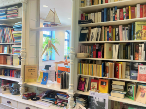 Regale mit Büchern, dazwischen ein Fenster mit einem kleinen Segelschiff auf einem Regal.
