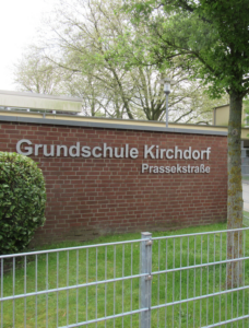 Rote Backsteinmauer am Eingang des Schulgeländes mit der Aufschrift Grundschule Kirchdorf Prassekstraße