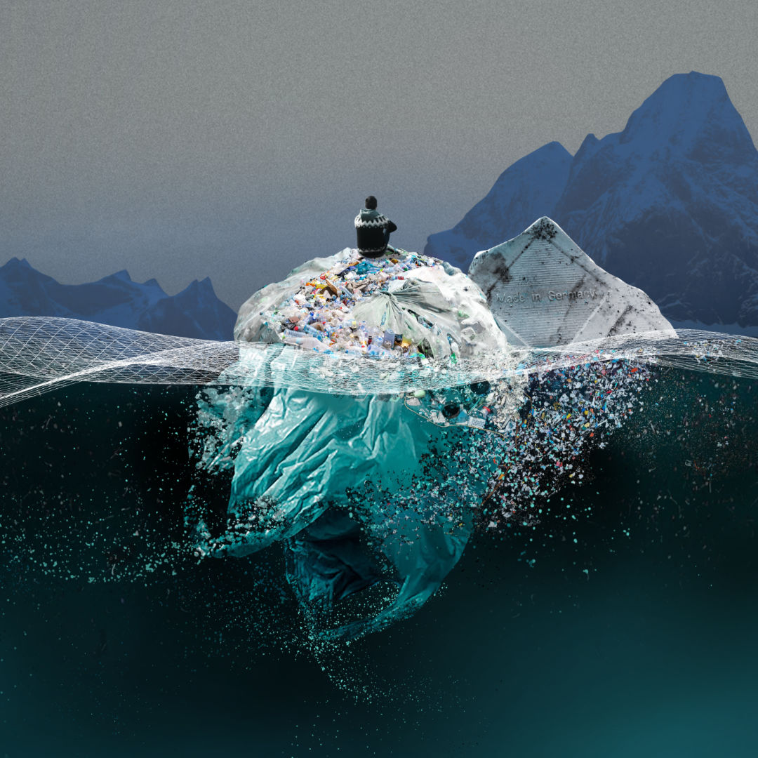 Im Ozean zwischen Eisbergen schwimmt eine riesige Kugel aus Plastik, auf der ein Mensch sitzt