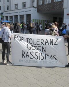 Zwei Demonstrant*innen mit einem Transparent mit der Aufschrift: "Für Toleranz gegen Rassismus"