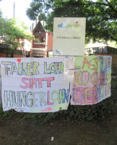 Transparente am Zaun vor einer Kita. Unter anderem mit der Aufschrift: Fairer Lohn statt Hungerlohn