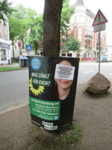 Wahlplakat der Grünen. Das Gesicht von Annalena Baerbock mit einem weien Zettel mit einem Kritik-Text überklebt