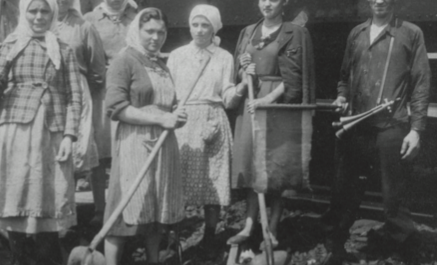 Altes Schwarz-Weiss-Foto: Frauen mit Kopftüchern und Arbeitsschürzen halten Schaufeln in den Händen.