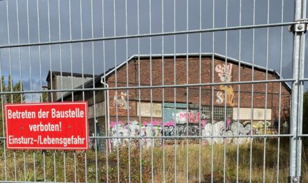 Alte Lagerhalle hinter Bauzaun