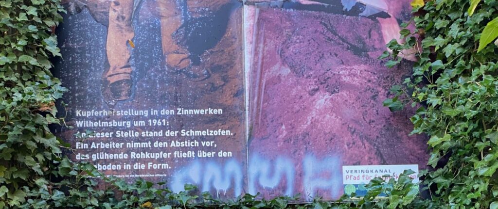 Großes Plakat in lila und Grüntönen mit Infos zu den Zinnwerken auf einer Hauswand