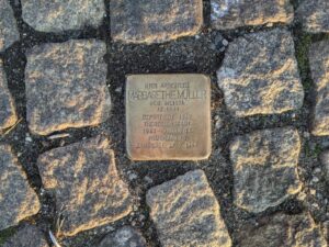 Ein Stolperstein mit edr Inschrift "Hier arbeitete Margarethe Müller, geb. Meissl, Jg. 1899, deportiert 1942 Theresienstadt, 1943 Ausschwitz, Neuengamme, ermordet 27.7.1944