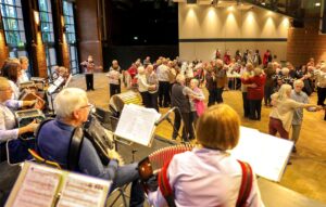 Ein Seniorenorchester spielt, andere Seniorinnen tanzen