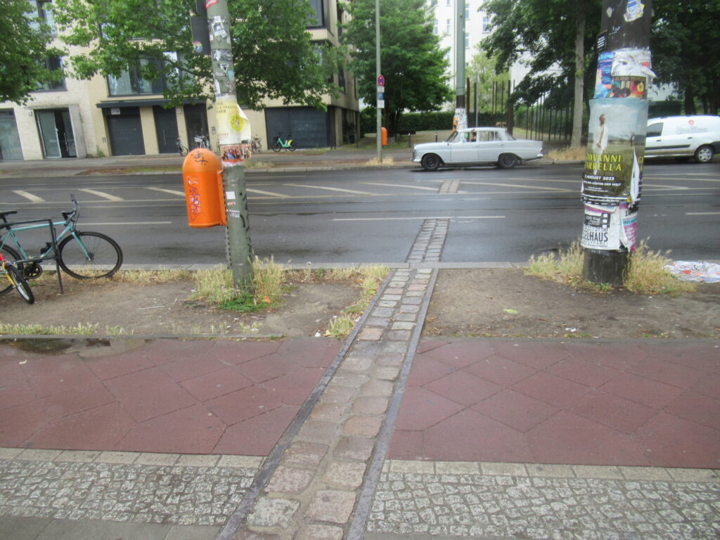 Ein gepflaster Streifen geht quer über Radfahrweg und Fahrbahn und spart nur die Straßenbahnschienen aus.