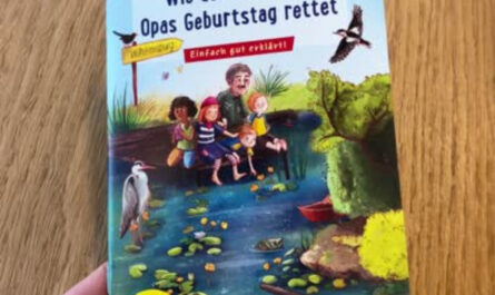 Ein Pixie-Buch auf einem Tisch, das ene Hand festhält. Titel des Buchs: Wie der Inselpark Opas Geburtstag rettete