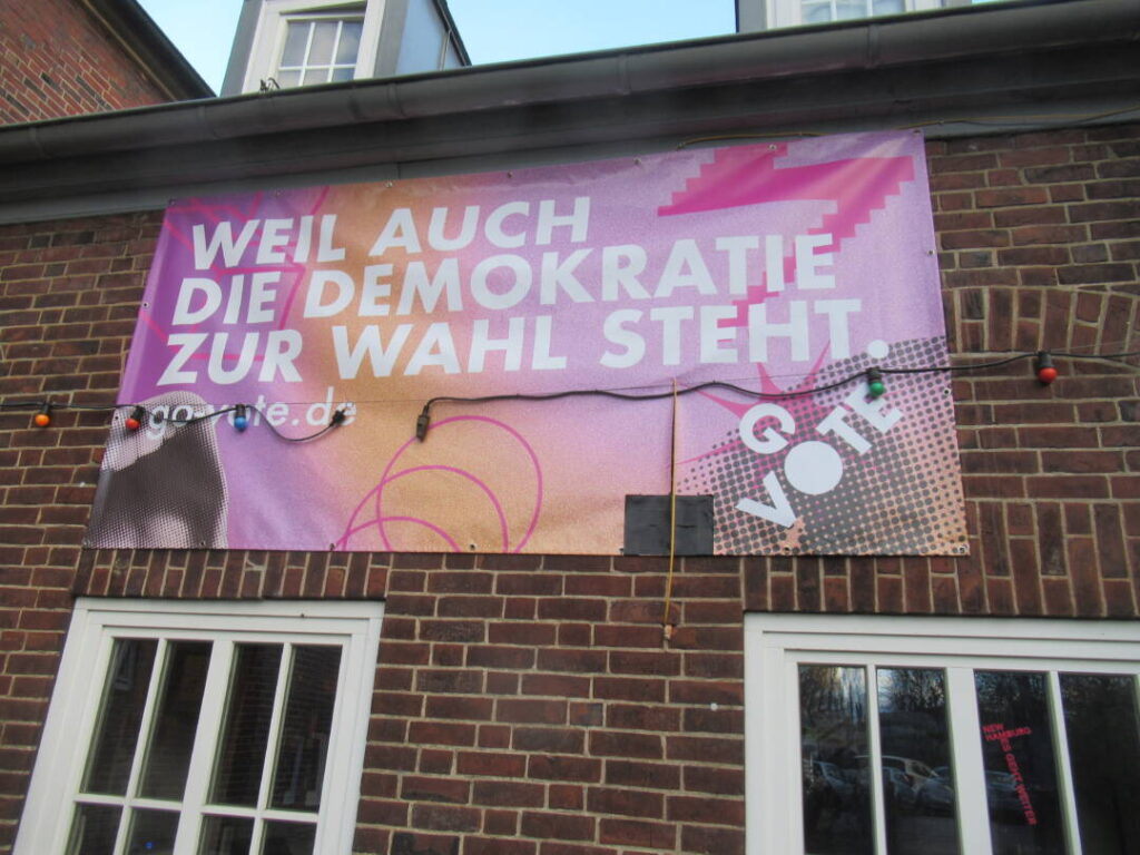 Transparent an der Hauswand mit der Aufschrift: Weil auch die Demokratie zur Wahl steht. 