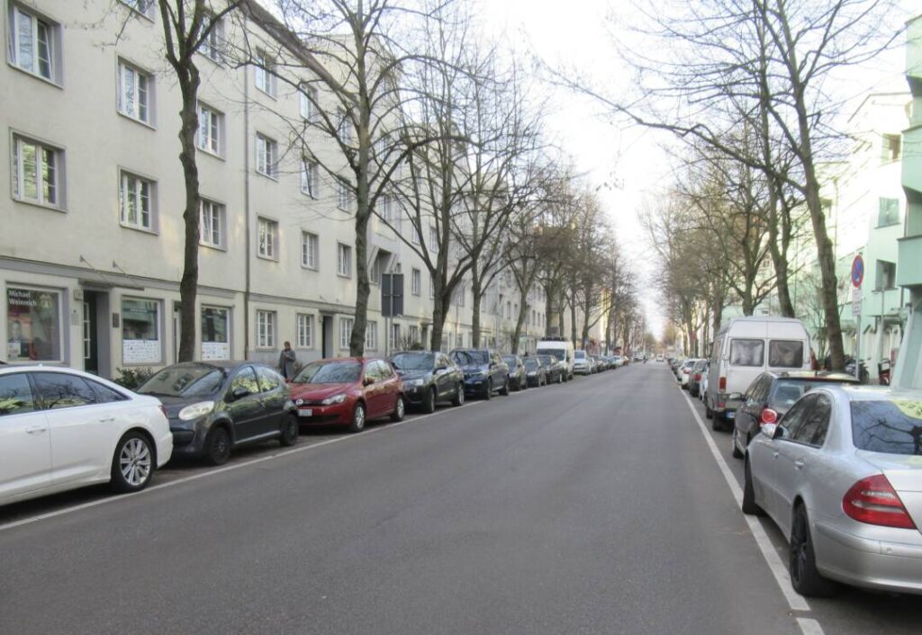 Blick durch die Veringstraße, von der Fahrbahn aus aufgenommen. Rechts und links lange Reihen parkender Autos.