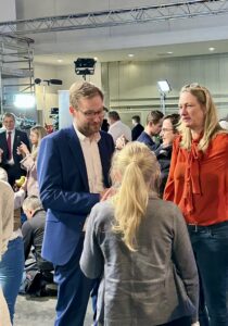 Viele Menschen in einer großen Halle. Im Vordergrund der Politiker Anjes Tjarks, der zwei Frauen ein Interview gibt.