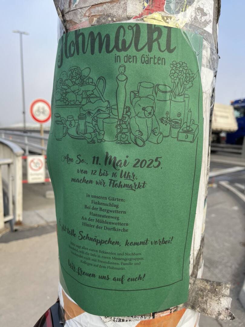 ein grünes Plakat mit schwarzer Schrift auf einem Laternenmast