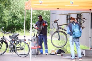 Menschen reparieren ihrer Fahrräder unter einem Pavillondach