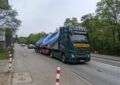 Ein großer LKW, der zwei Pools geladen hat, fährt durch eine schmale Straße