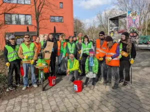 Menschen in grünen Warnwesten stehen mit roten Eimern vor einem roten Haus