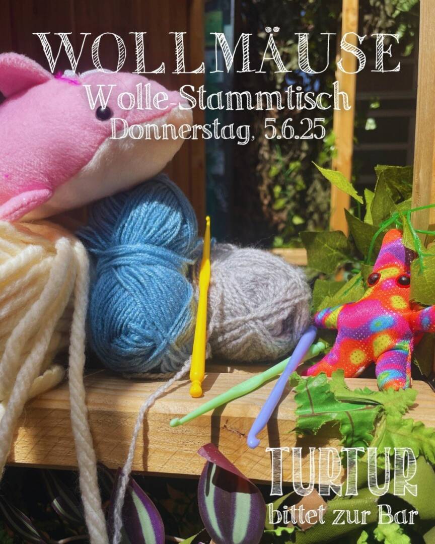 Verschiedene bunte Wollknäuel, Stricknadeln und ein Kuscheltier-Wal liegen auf einem Tisch