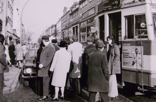 Schwarzweißfoto: eine Menschengruppe vor der Straßenbahn