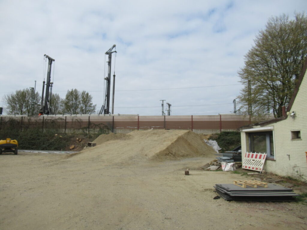 Blick auf die Lärmschutzwände am Bahndamm und auf eine aufgeschüttete Rampe zum Bahndamm für die Baufahrzeuge
