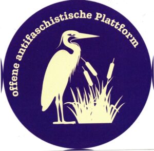 Ein dunkelblauer runer Klebezettel mit einem weißen Reiher in der Mitte, davor eine Rohrkolbenpflanze. oben rund: offene antifaschistische Plattform in weiß.