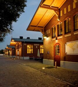 In der Dämmerung vier beleuchtete Vorderfronten der Backsteingebäude der BallinStadt.