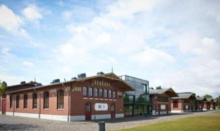 BAcksteingebäude. Davor eine Wiese und darüber blauer Himmel mit weißen Wolken.