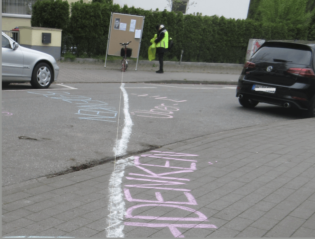 Mit weißeer Kreide eine Linie diagonal über die Fahrbahn zu den Stolpersteinen hin aufgemalt. Daben in farbiger Kreide die Wörter DENKEN, BEDENKEN und ÜBERDENKEN