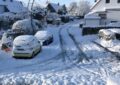Ausschnitt: Blick vom Kopf einer Sackgasse in einer Wohnstraße mit kleinen Doppelhäusern im Schnee. Die Straße ist vereist mit Spurrillen. Die Sonne scheint.