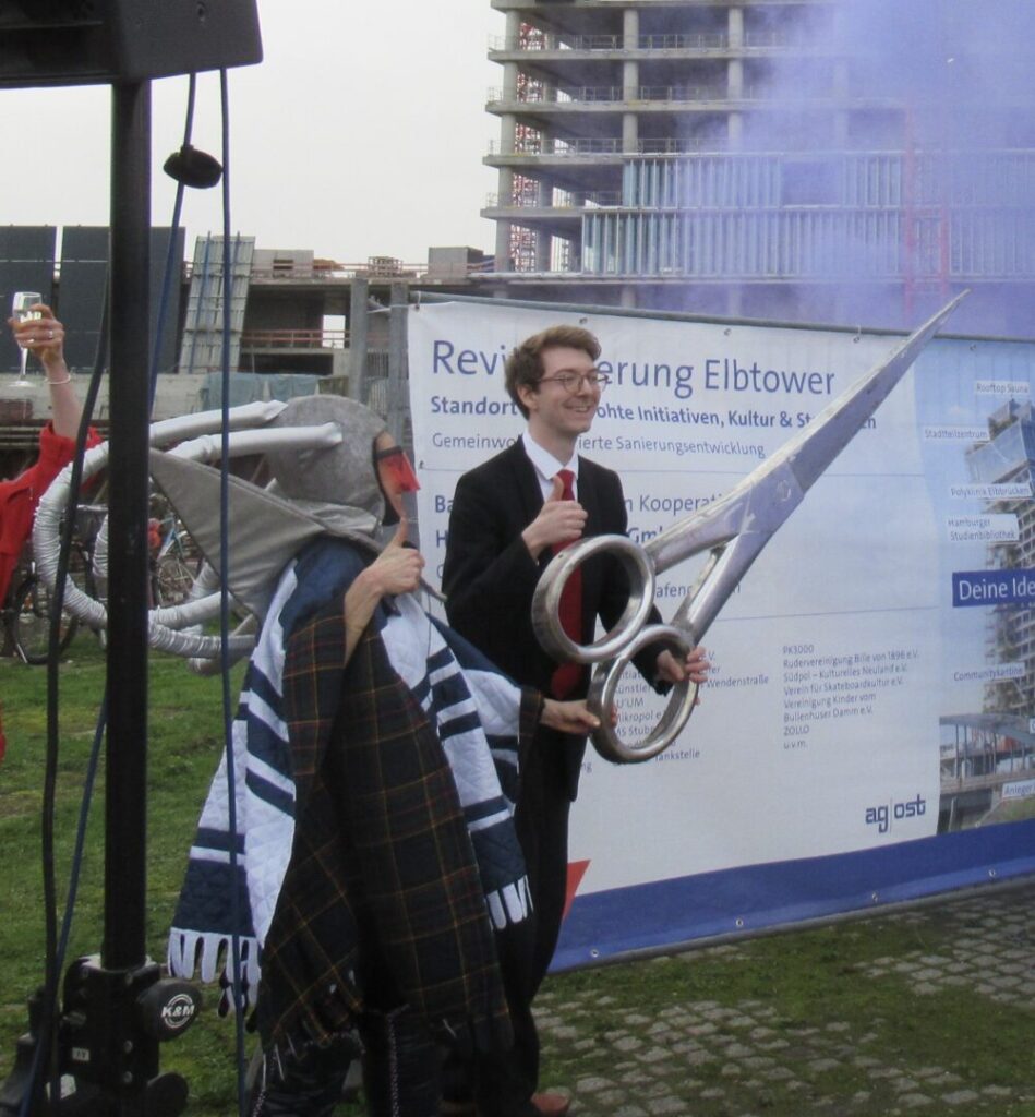 Gespielte Einweihung mit einem Mutgied der Ag Ost als Senator mit überdimensionaler Schere