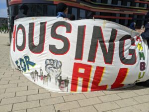 Auf einem großen Transparent steht „Housing for All"
