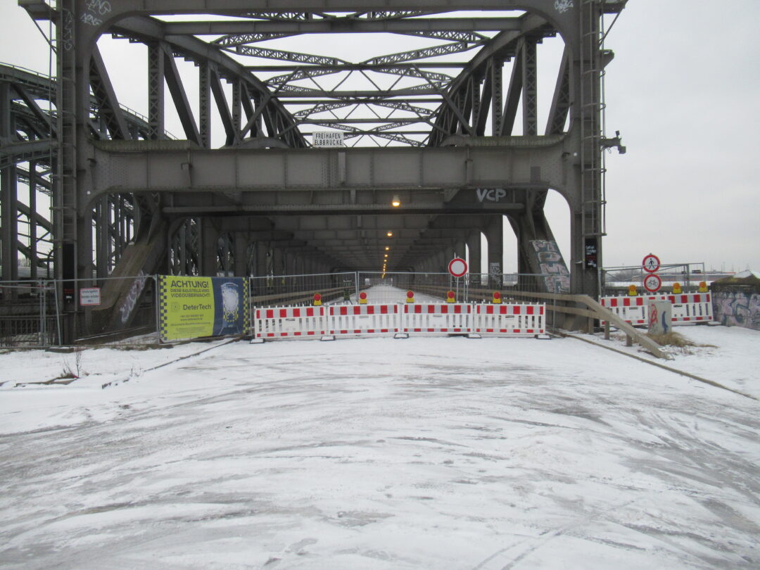 Die Straße endet vpr der Brücke vor einem Zaun mit rot-weißen Absperrgitter