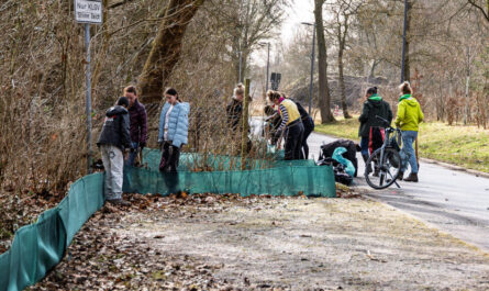 Ca. 10 Menschen bauen einen ca. 50-cm-hohen-Textilzaun am Straßenrand auf. Foto: Heinz_Brossolat/BUND HH