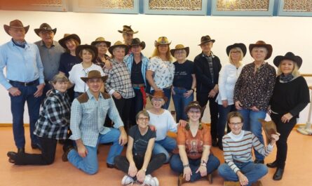 Gruppenfoto: Die Büwi Line Dancers (ca. 20 von ihnen) posieren vor einer Wand. Alle tragen Cowboy-Hüte, aber sie haben normale Kleidung an, nicht wie bei den Auftritten alle ein weißes Hemd. Foto: Melanie Brito