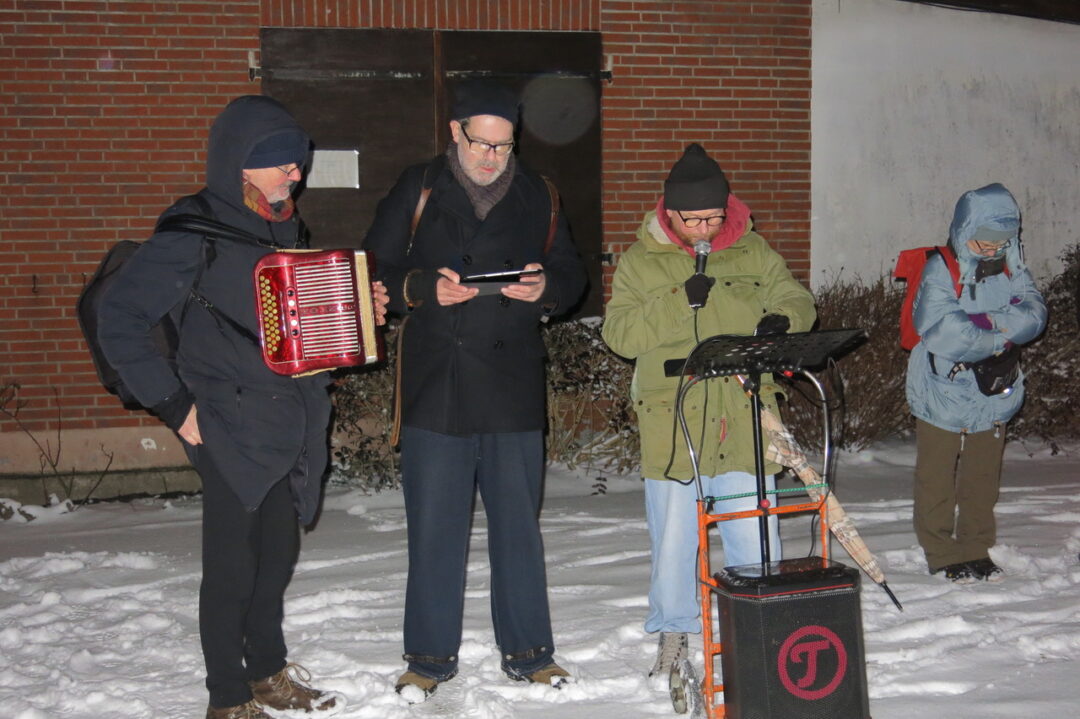Maco Moreno und Oliver Menk lesend im Vordergrund, daneben Ulrich Kodjo Wendt mit Akkordeon