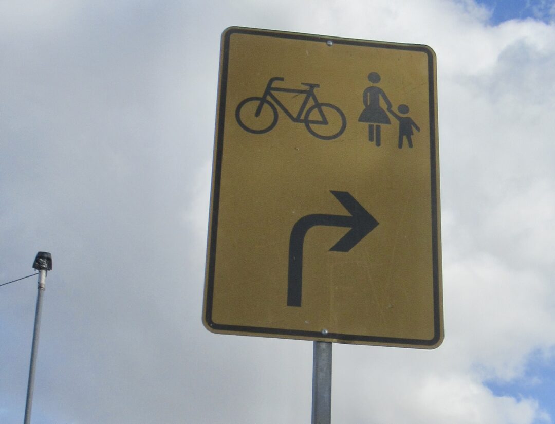 Gelbes Schild mit Rechtsabbiegepfeil und Fahrrad- und Fußgängersymbol
