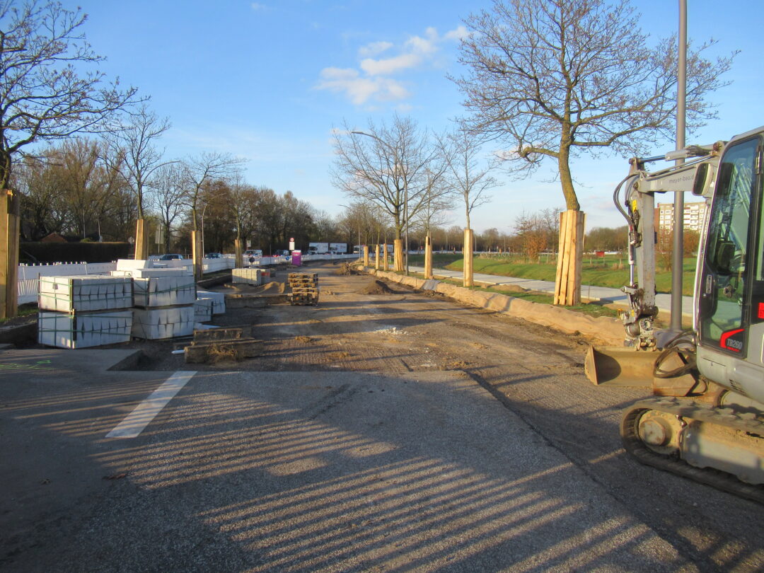 Blick auf die aufgegrabene Straße rechts und links mit Brettern geschützte Bäume 