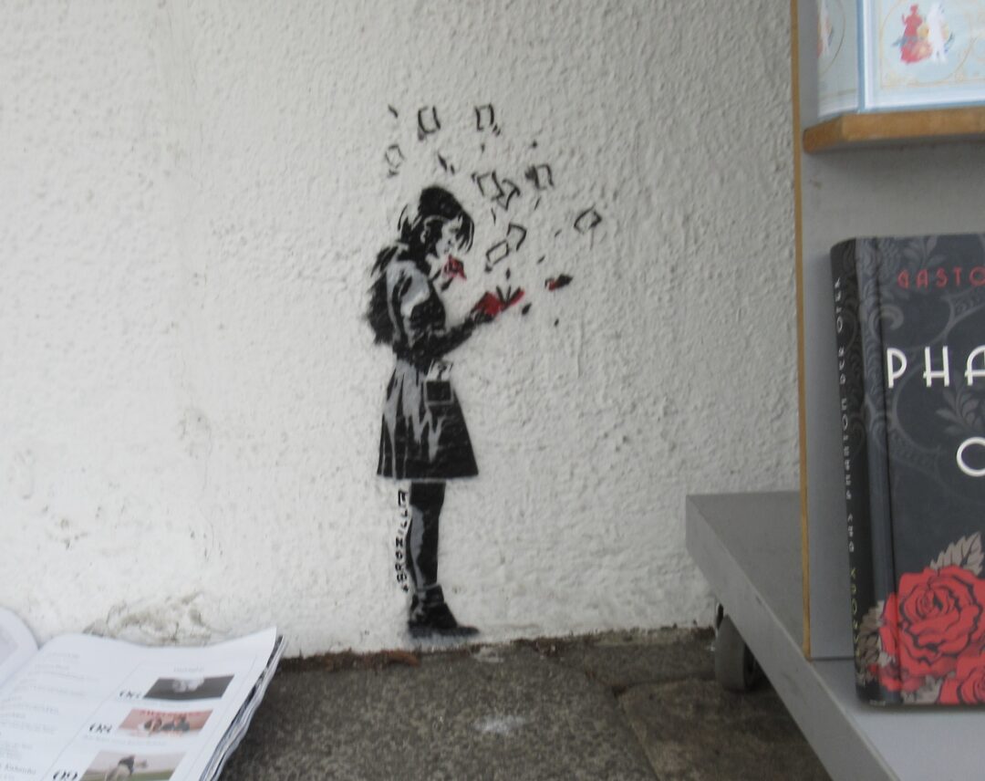 Kleine schwarze Figur des Mädchens Pepper im Profil mit rotem Buch in der Hand. an die Wand gesorayt