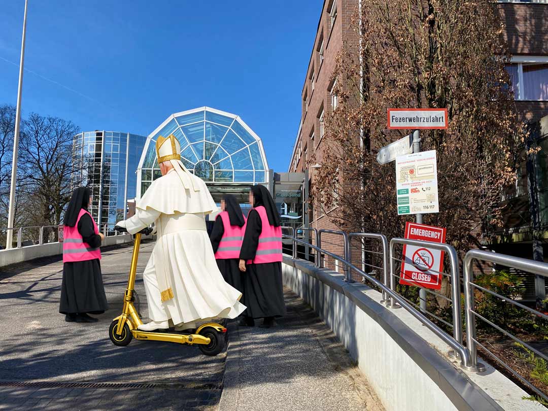 Der Papst auf goldenem E-Scooter mit Nonnen. Quelle: Chat-GPT/Marianne Groß. Composing: Meret Büchner