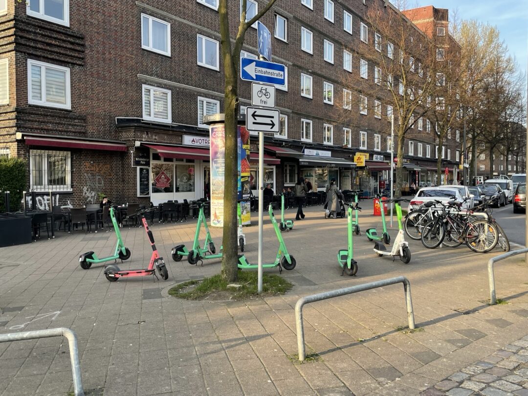 Straßenszene auf der Veddel: In Bahnhofsnähe stehen 11 E-Scooter sehr unordentlich auf einer recht großen Fläche auf dem Gehweg. Foto: A. Becker