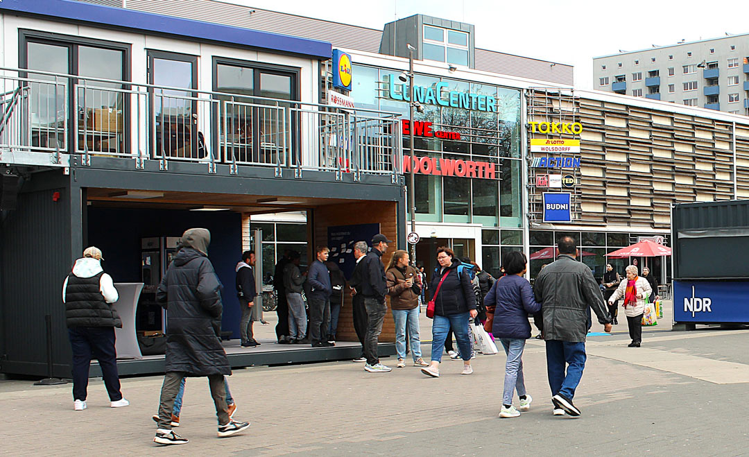 Menschen eilen zwischen den NDR-Containern hindurch, einige stehen aber auch in dem zweistöckigen Container und unterhalten sich. Foto: Melanie Brito